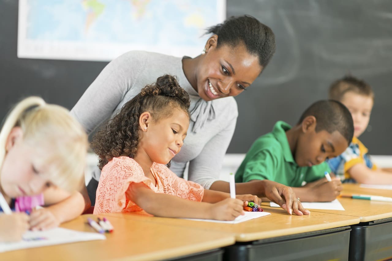 Teacher assisting elementary student