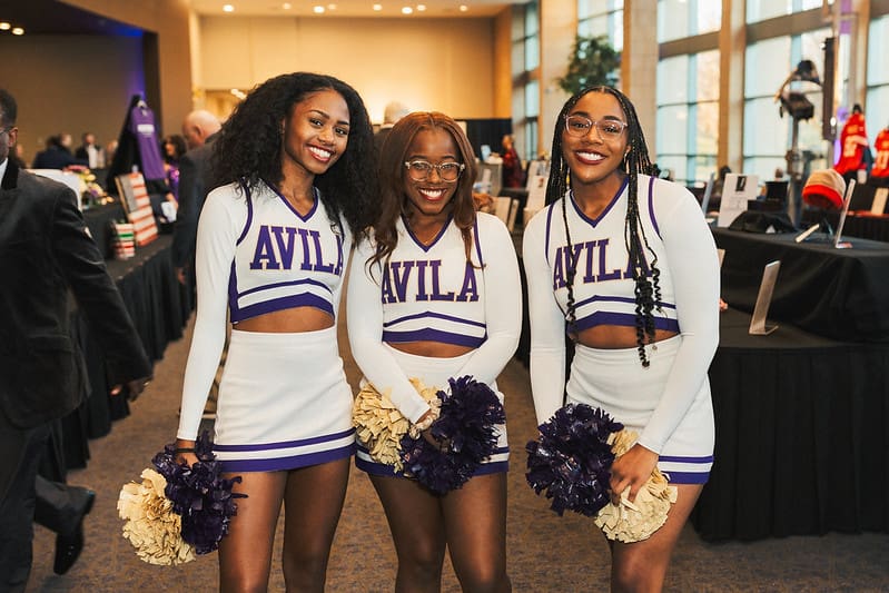 Three cheerleaders smiling with pom-poms