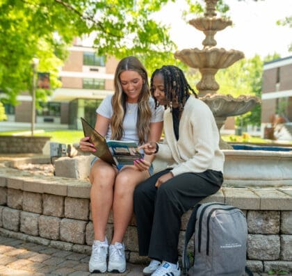 Two students studying while sitting at fountain