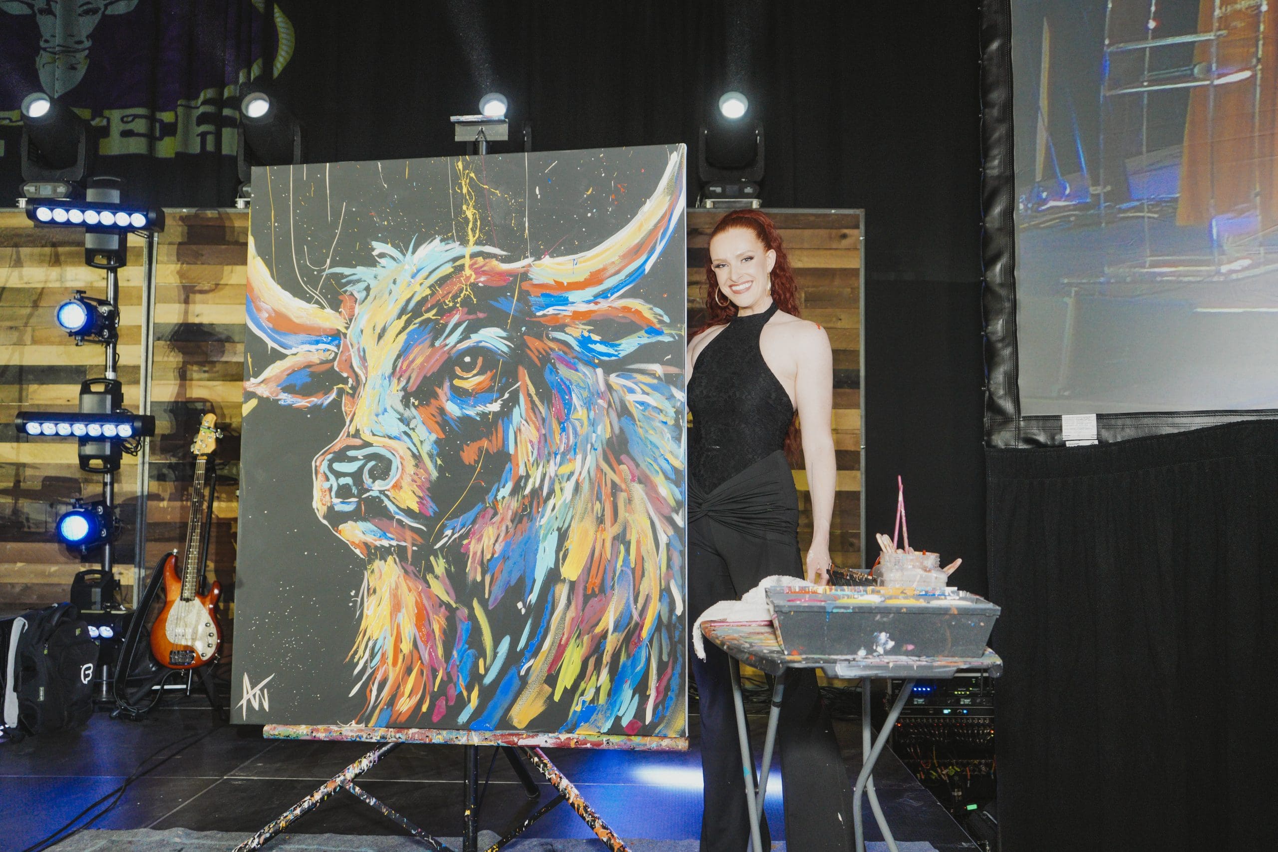 Artist posing beside a colorful painted longhorn bull canvas at the Avila University Steer Dinner