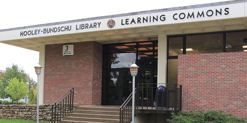 Exterior entrance of the Hooley-Bundschu Library & Learning Commons on the Avila University campus, featuring brick walls, stairs and ramp access, and the library name displayed above the entrance.