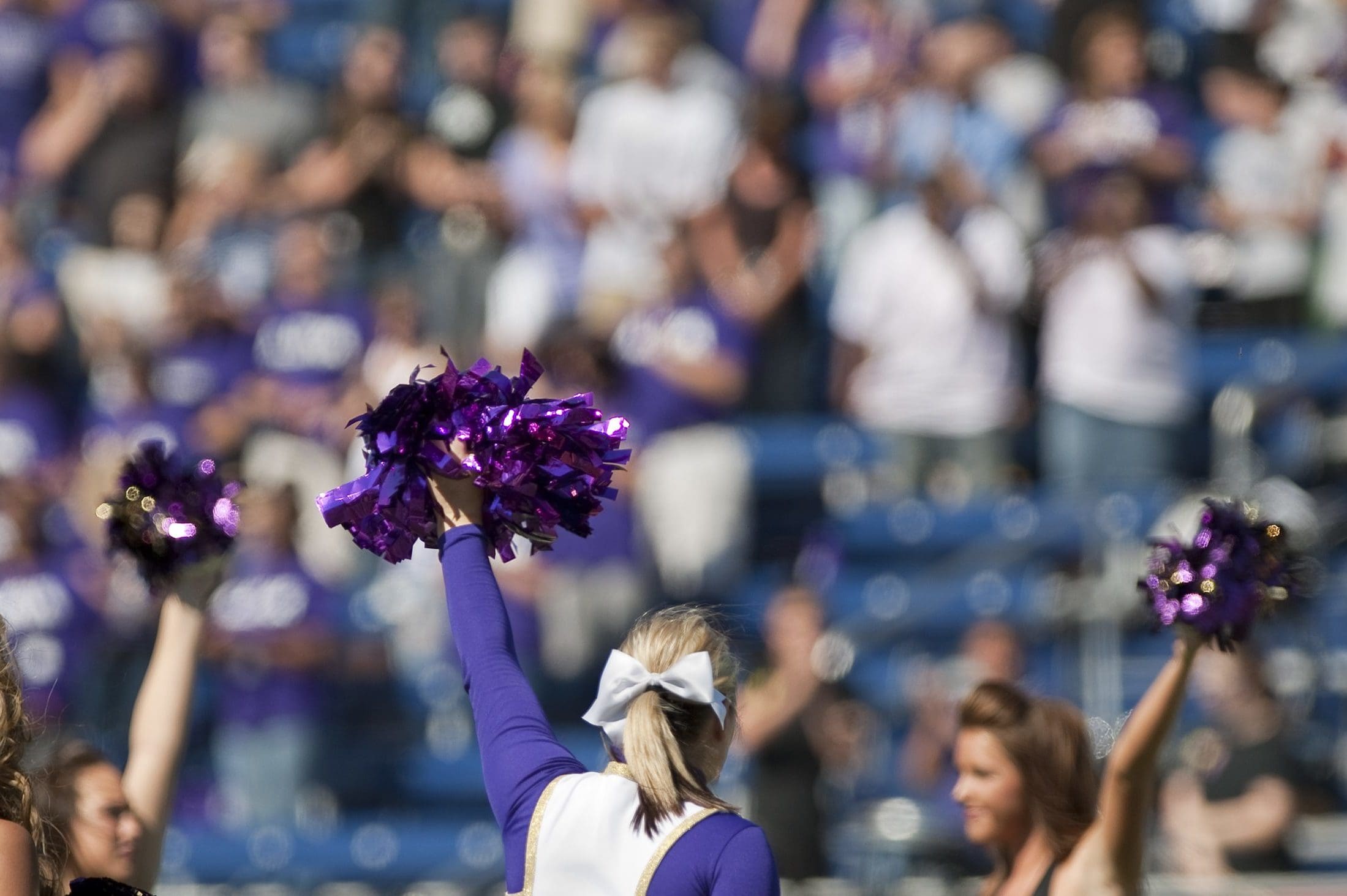 Avila University cheerleaders performing with purple pom-poms at an Eagles athletics event