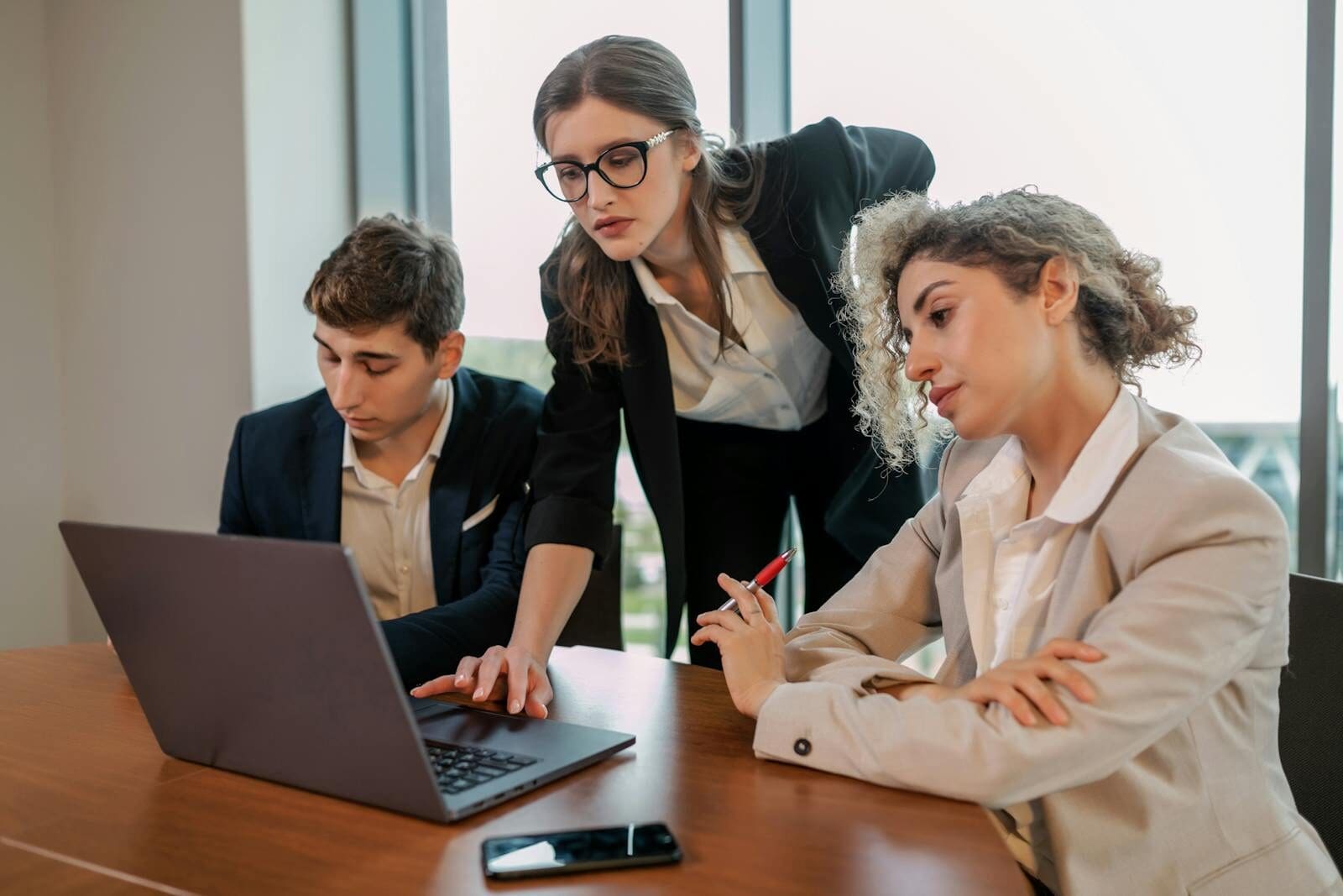 Diverse team working on a project together at an office desk with a laptop.