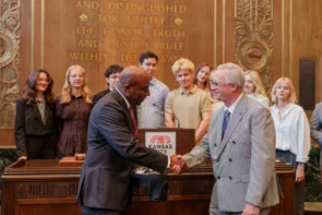 Avila University President Dr. Todd Pfannestiel shaking hands with Kansas City Mayor Quinton Lucas at Kansas City Hall, surrounded by INSPIRE International Exchange Program students during their July 2026 visit