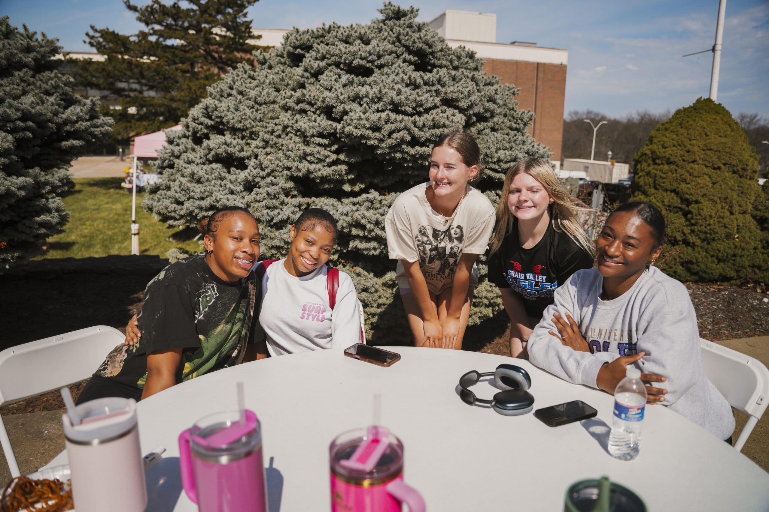 Group of Avila University students smiling together at an outdoor table during a campus event