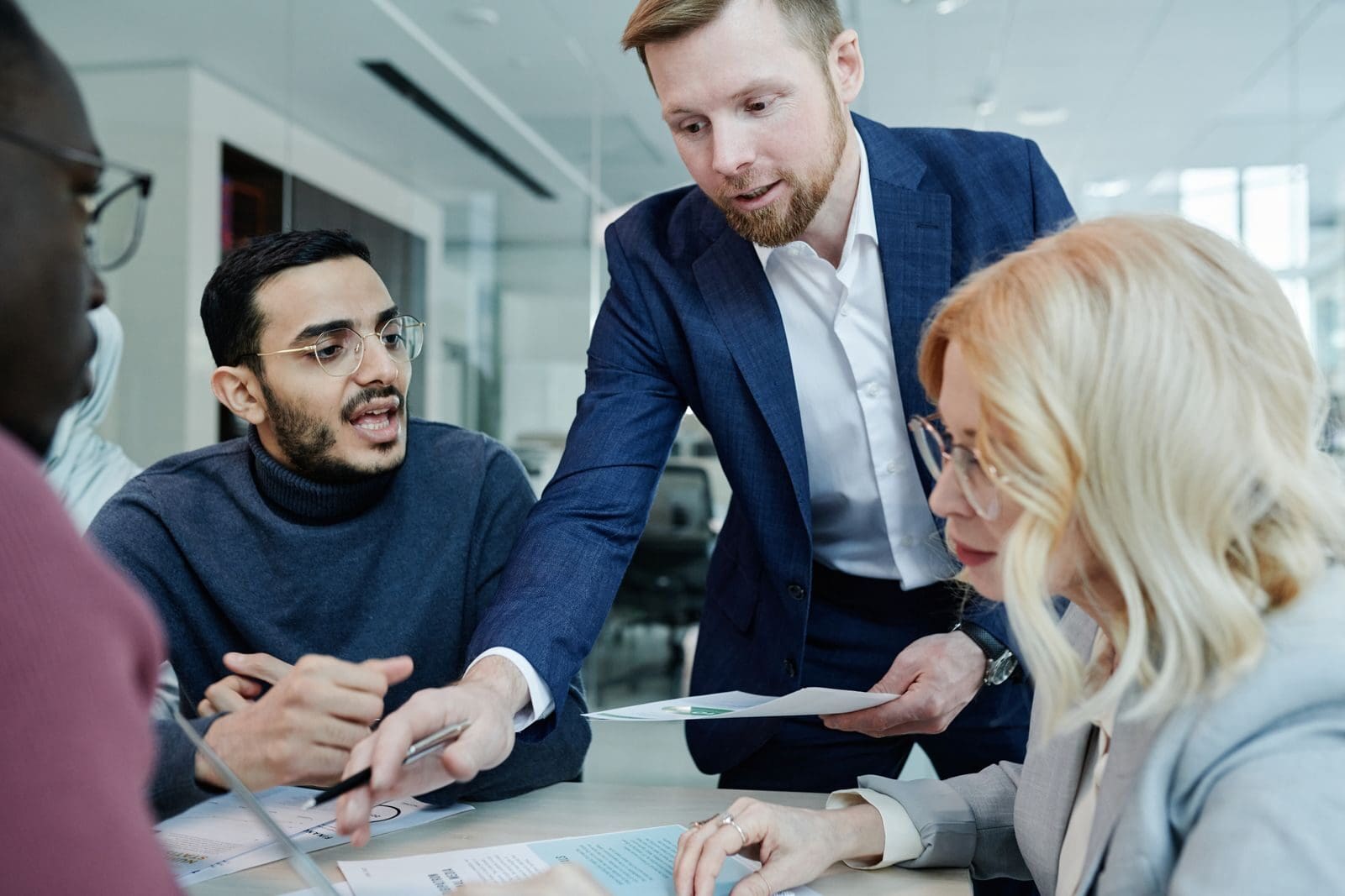 A diverse group of colleagues discussing ideas during a team meeting in a modern office setting.